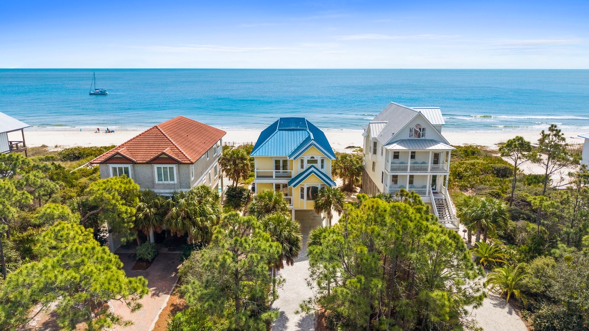 Coastal vacation homes nestled among tropical palms offer stunning beachfront access with pristine waters and sandy shores just steps away.