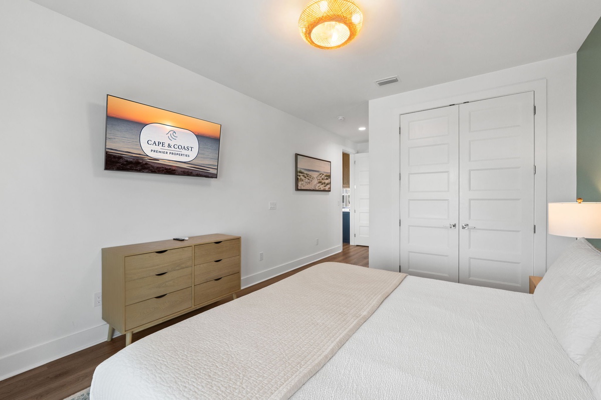 Your peaceful retreat awaits with a plush bed, ample storage in the mid-century dresser, and a warm woven light fixture overhead. Closet space keeps everything tidy during your stay.