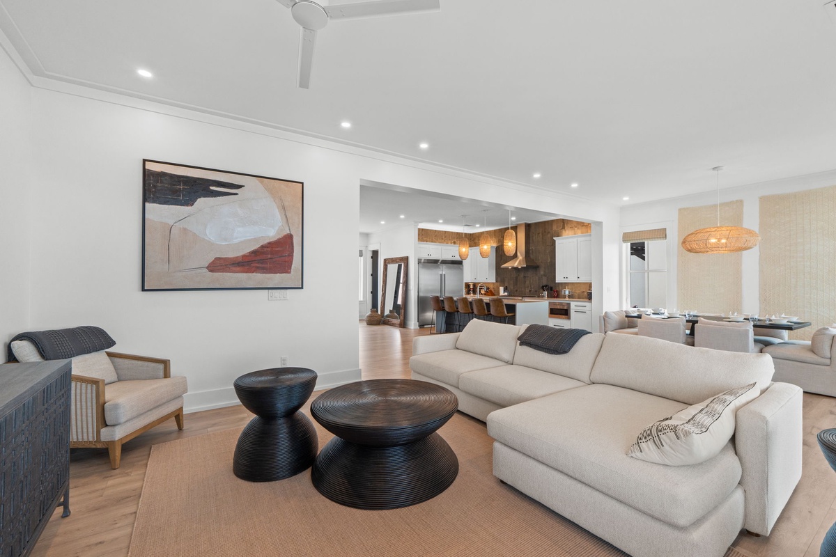 Sink into plush seating where your group can gather, framed by coastal art and open views to the kitchen and dining areas—a perfect spot for your morning coffee.