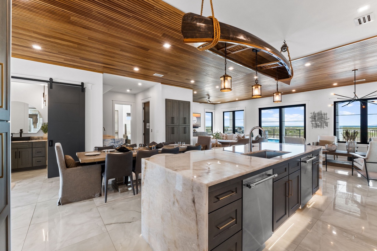 Step into this coastal retreat where a stunning open-concept design brings together your kitchen, dining, and living spaces under beautiful wood ceilings. The island becomes your gathering spot as natural light streams through expansive windows.