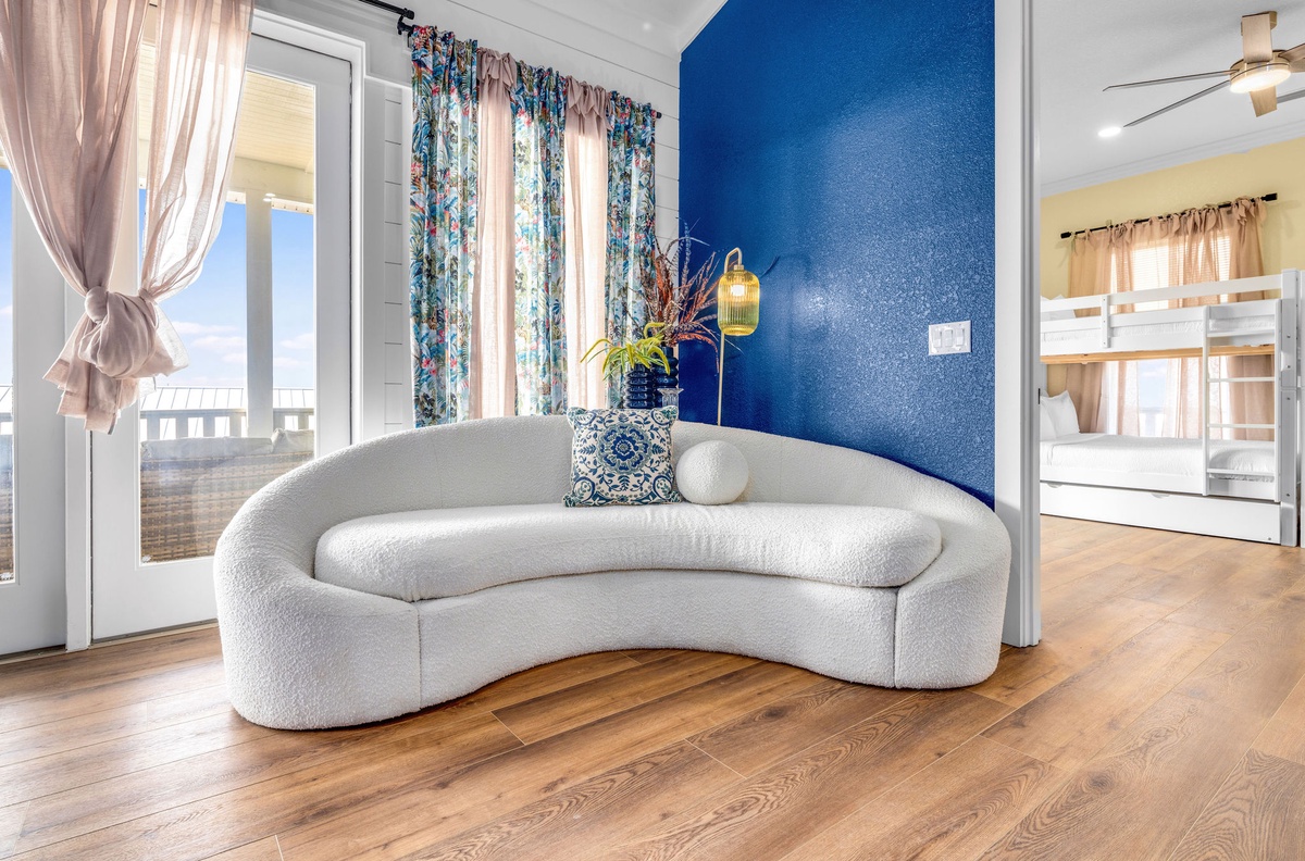 Sink into this curved sofa where vibrant blue walls create a calming backdrop. Your stylish retreat features bunk beds and opens to bright spaces.