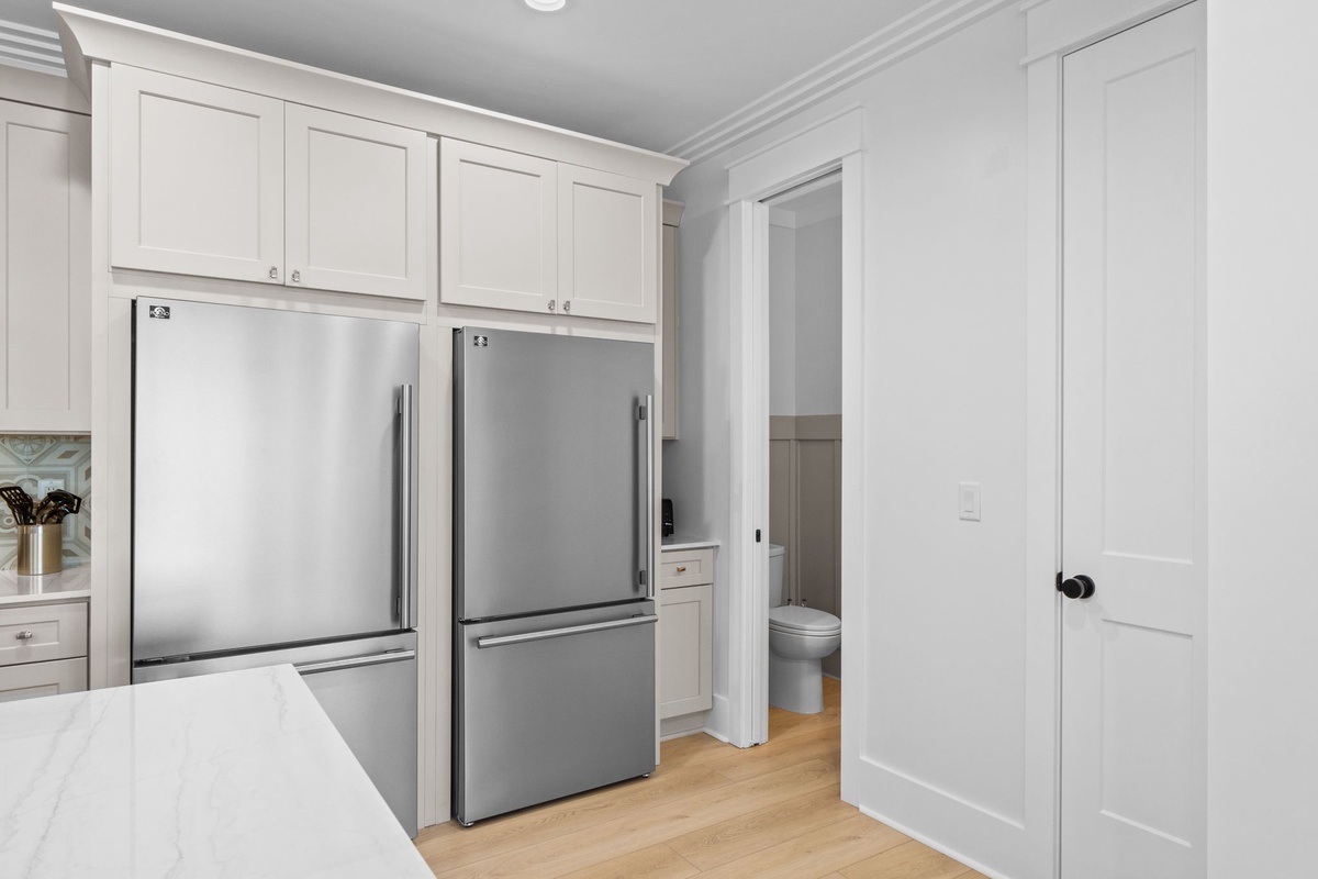 Your fully equipped kitchen boasts elegant white cabinetry, double stainless steel refrigerators, and marble countertops—perfect for preparing meals during your stay.