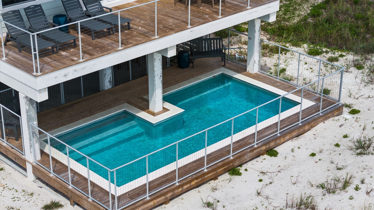 Aerial view of a beachfront vacation rental featuring a private swimming pool with deck and an elevated sun terrace adjacent to natural coastal dunes.