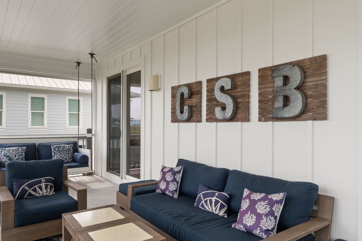 Relax on the covered porch with comfy seating and charming coastal decor—your peaceful retreat awaits.