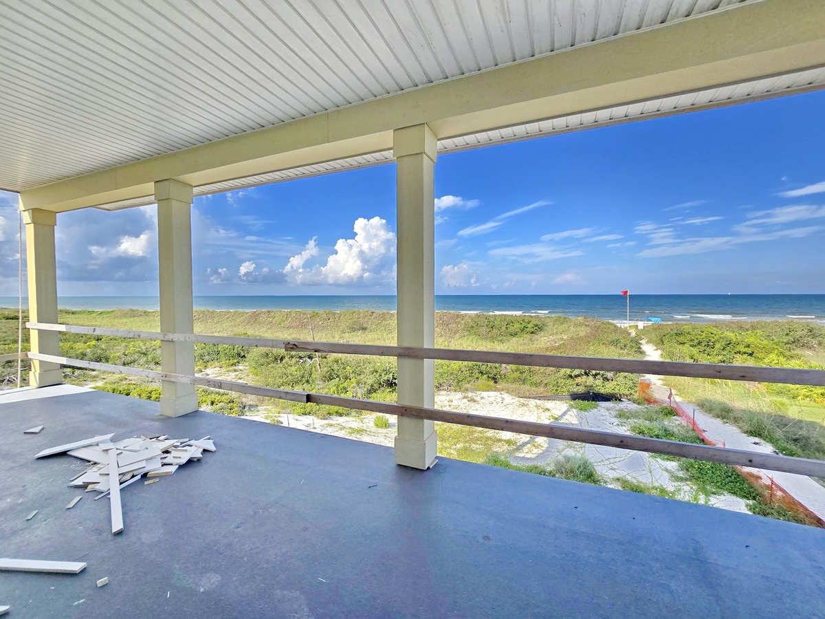 Expansive beachfront views stretch across the horizon from this covered outdoor space, with natural dunes and coastal vegetation framing the serene oceanfront setting.
