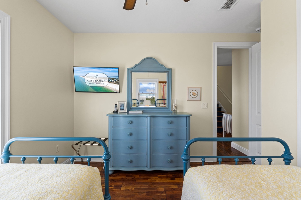 You'll love the coastal charm of this twin bedroom, where vintage-style blue metal beds meet a matching dresser and mirror. Warm wood floors and beamed ceilings add character.