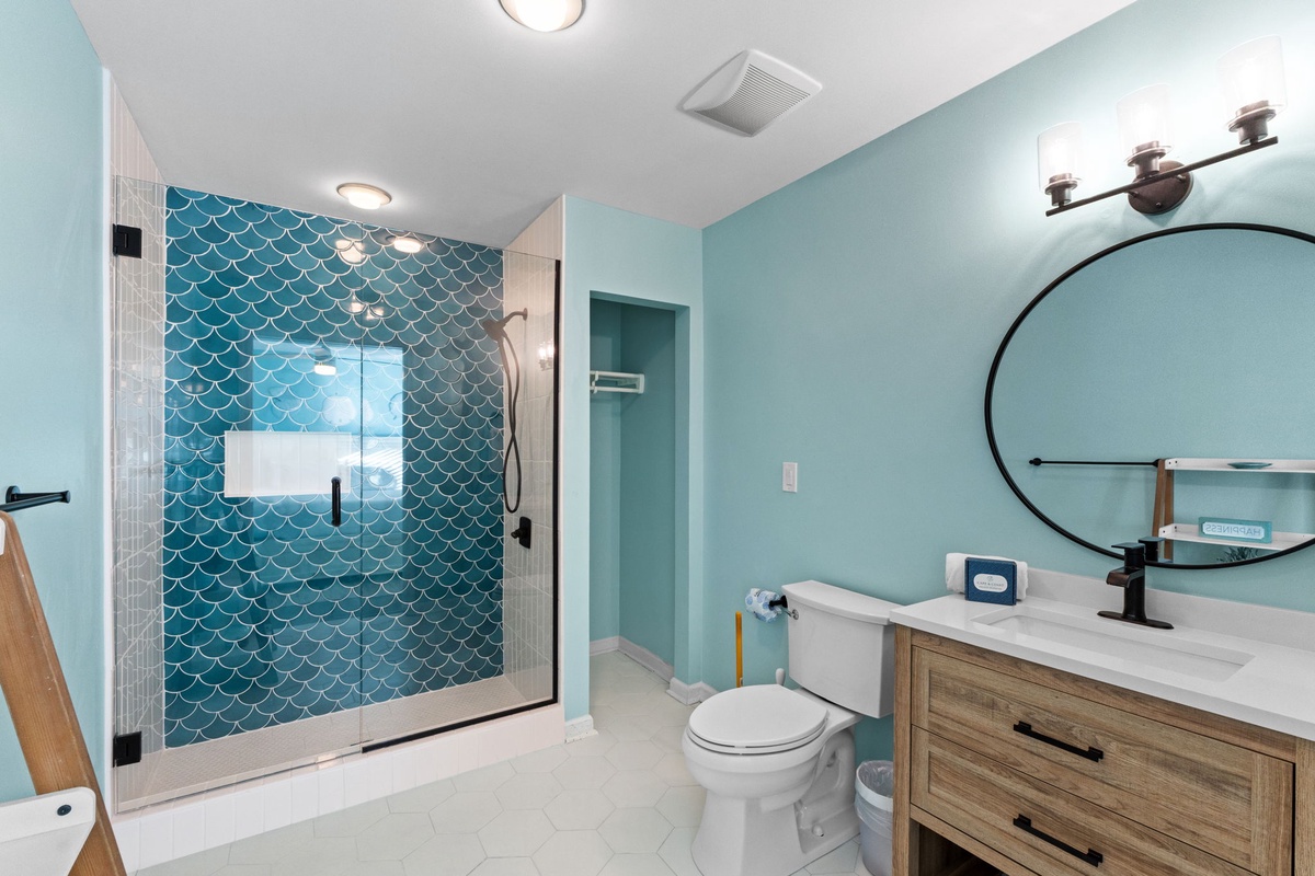 Your stylish bathroom features ocean-inspired teal tiles, a spacious walk-in shower, and modern vanity—perfect for refreshing after beach days.