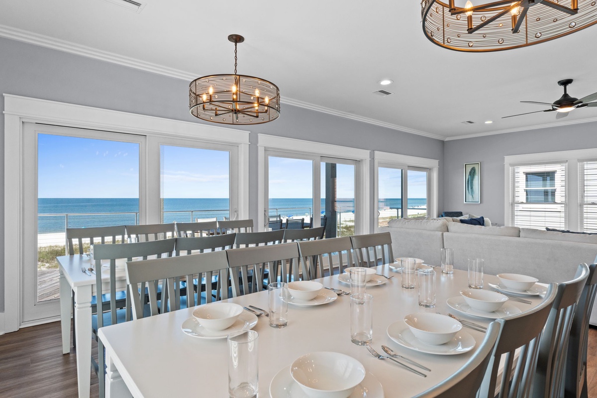 Gather around this spacious dining table with stunning ocean views framed by large windows. The elegant chandelier and coastal décor create the perfect setting for memorable meals with your group.