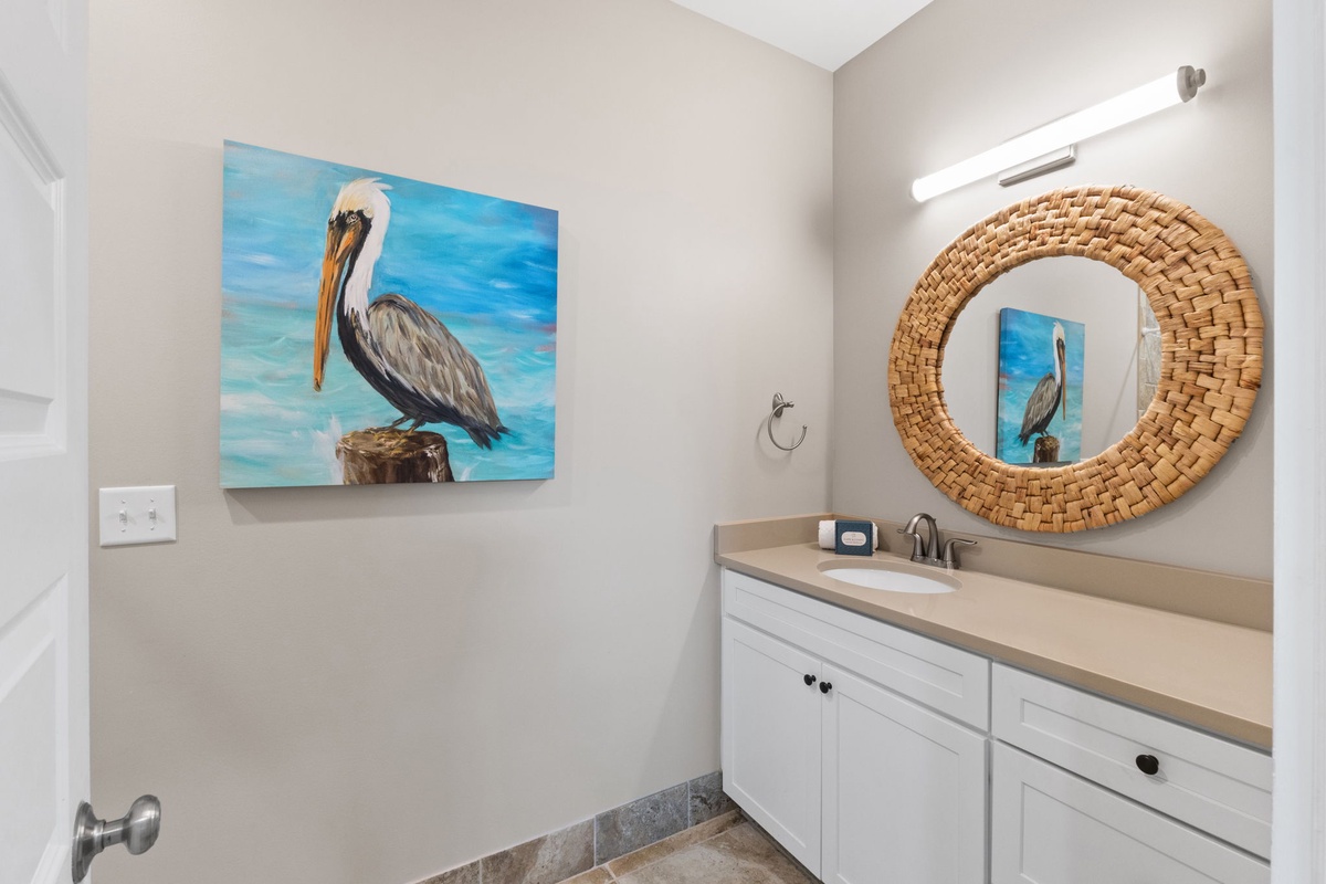Freshen up in your coastal-inspired bathroom, where vibrant pelican artwork and a handwoven mirror set a warm, beachy tone for your stay.