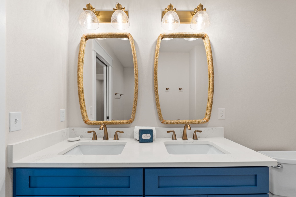 Dual vanity with gold-framed mirrors and brass fixtures offers you a stylish morning routine in this bright, contemporary bathroom.