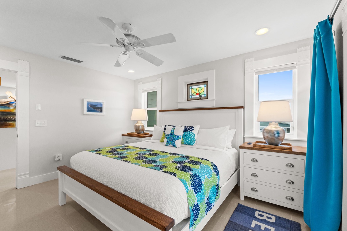 Drift off to sleep in this bright, coastal bedroom where ocean breezes from your ceiling fan and glimpses of blue through the window create your perfect seaside retreat.