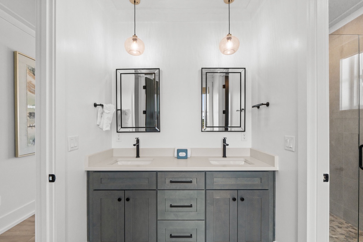 Refresh in your private dual-sink bathroom, featuring warm pendant lighting, modern fixtures, and a sleek vanity—perfect for getting ready each morning.