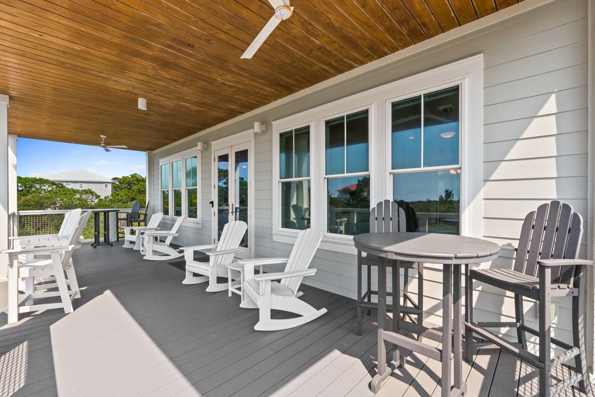 Unwind in your private balcony retreat, where coastal breezes flow through rocking chairs and the warm wood ceiling creates a perfect space for morning coffee or evening conversations.