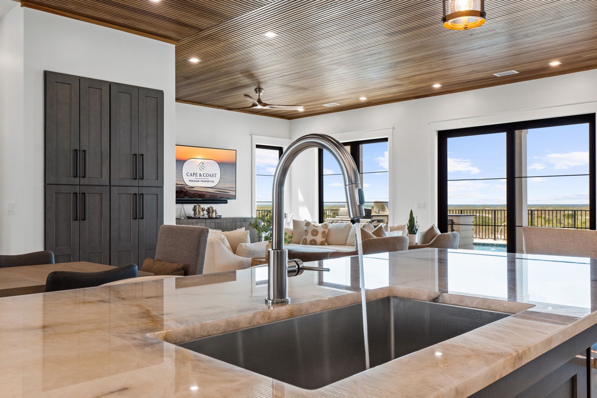 Enjoy seamless open-concept living where your kitchen flows into a welcoming lounge with pool access, all beneath a striking wood-paneled ceiling that adds warmth to every gathering.