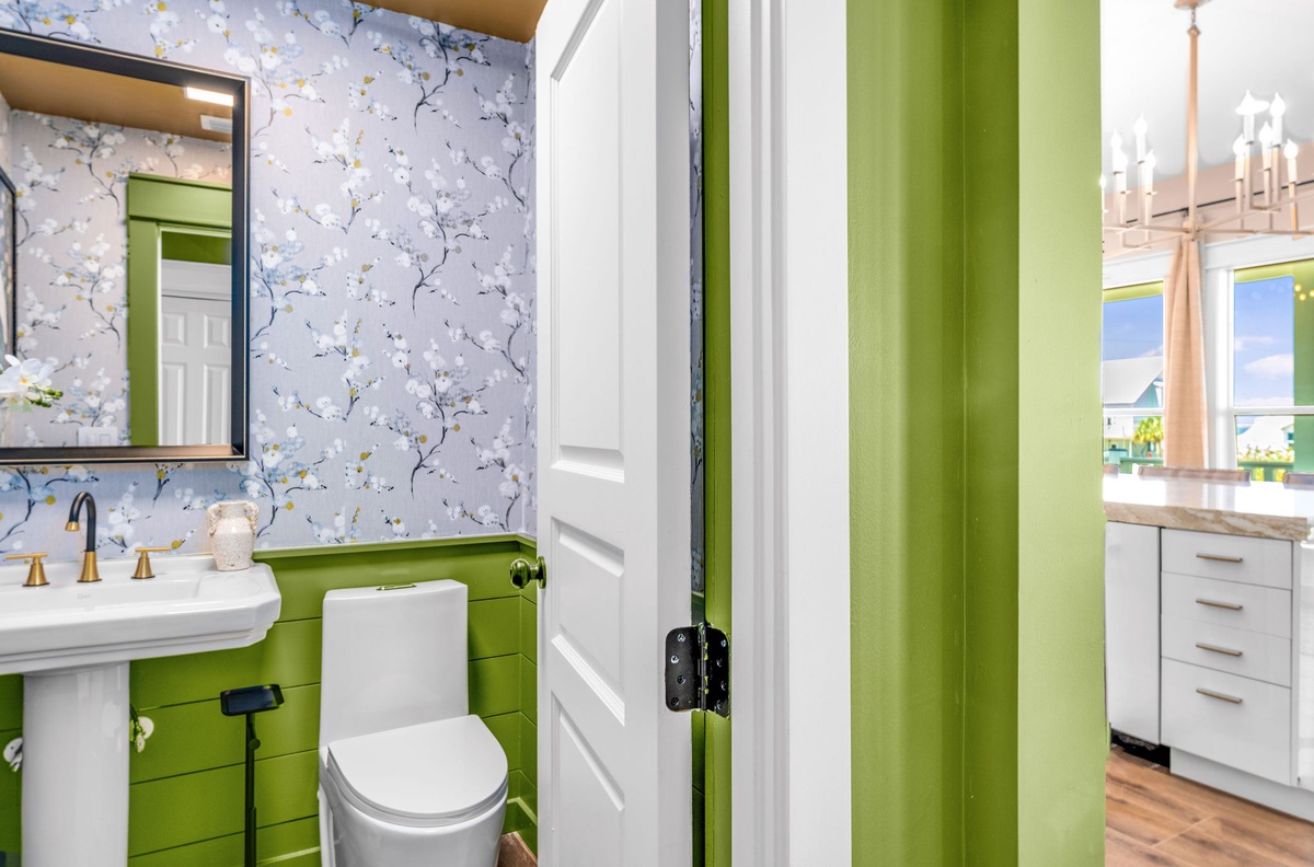 Your stylish powder room features charming floral wallpaper and fresh green accents for a cheerful start to your day.