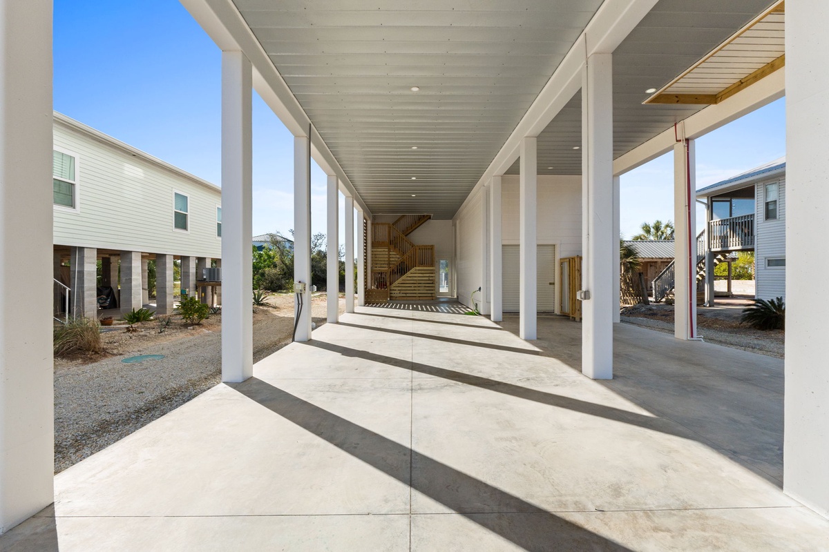 Covered parking and entrance area with modern architectural columns and clean concrete flooring.