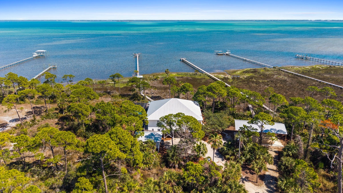 Stunning waterfront property nestled among lush trees with private docks extending into crystal-clear turquoise waters.