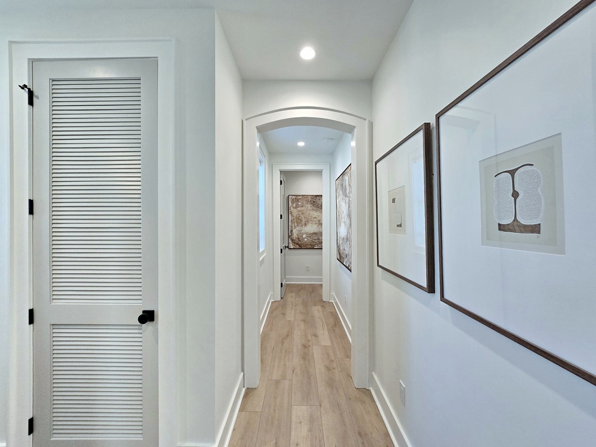 Walk through your bright, welcoming hallway with warm wood floors and charming artwork guiding your way to comfortable spaces.
