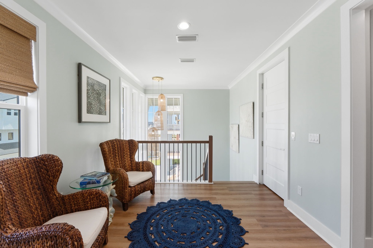 Settle into your private upstairs retreat, where coastal breezes and natural light welcome you. Warm woven chairs and soft, serene tones create your perfect escape.