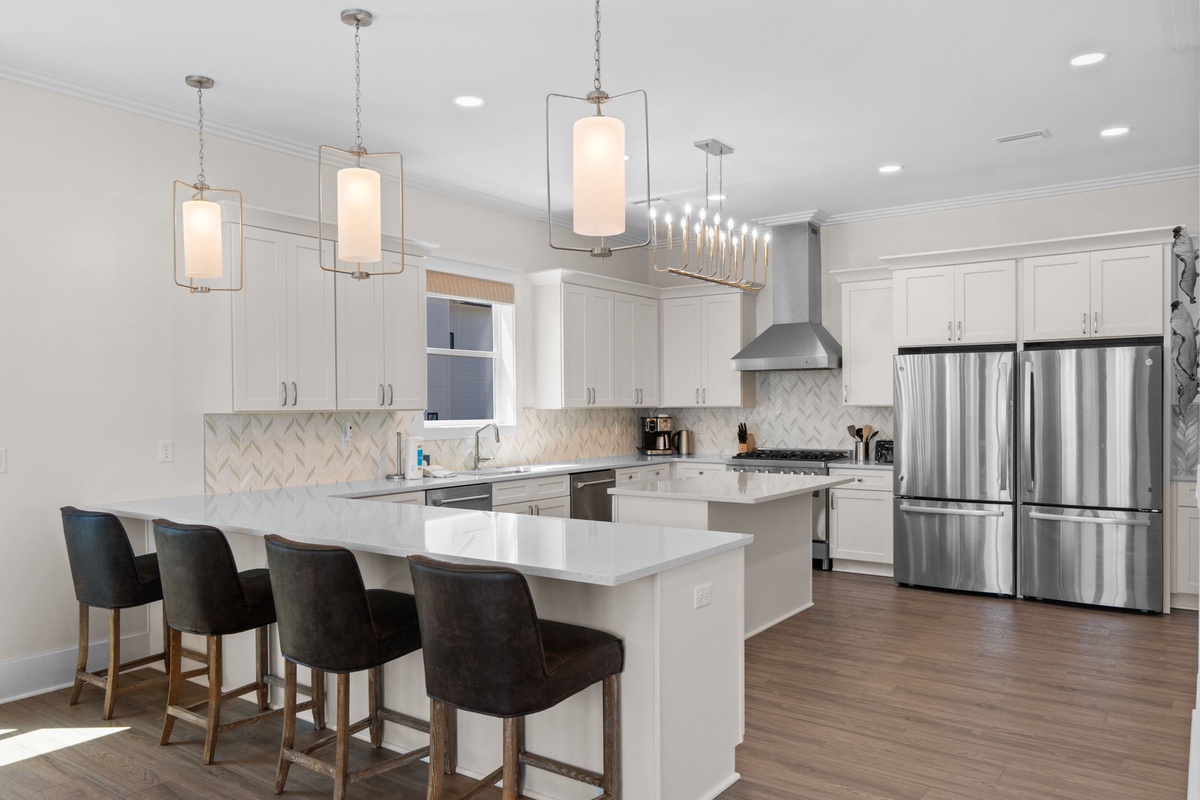 Step into your bright, modern kitchen where sleek white cabinetry meets gleaming quartz countertops and designer lighting creates the perfect ambiance for memorable meals together.