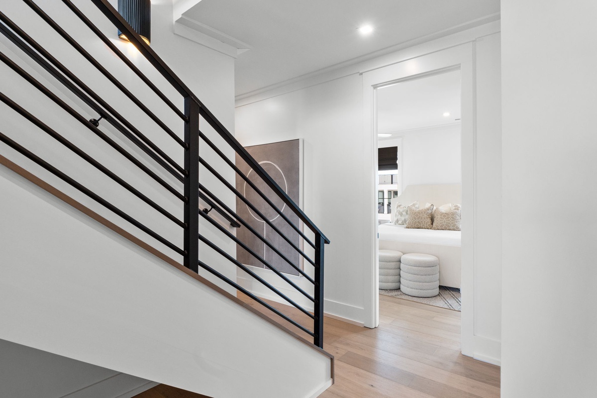 Step into your private retreat through this sleek hallway. The modern staircase leads to more space, while your cozy bedroom awaits with soft textures and serene comfort.