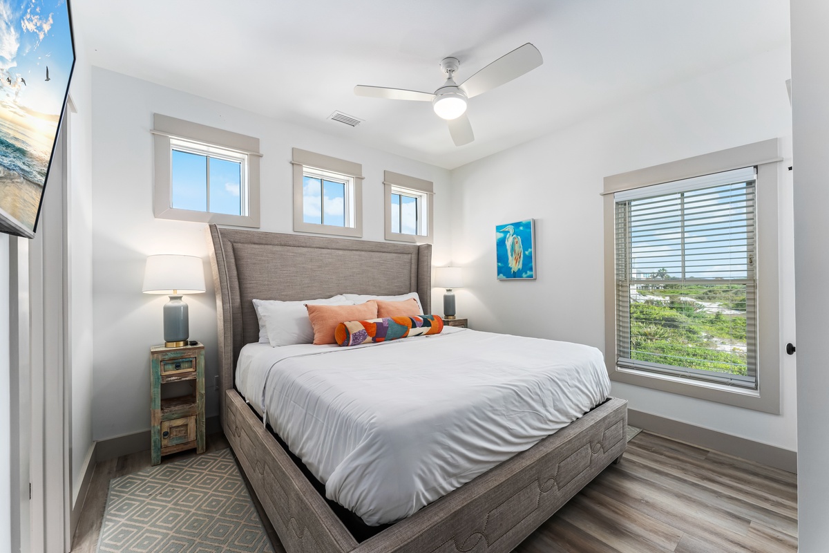 Rest peacefully in your cozy bedroom with natural light streaming through multiple windows and views of the surrounding landscape.