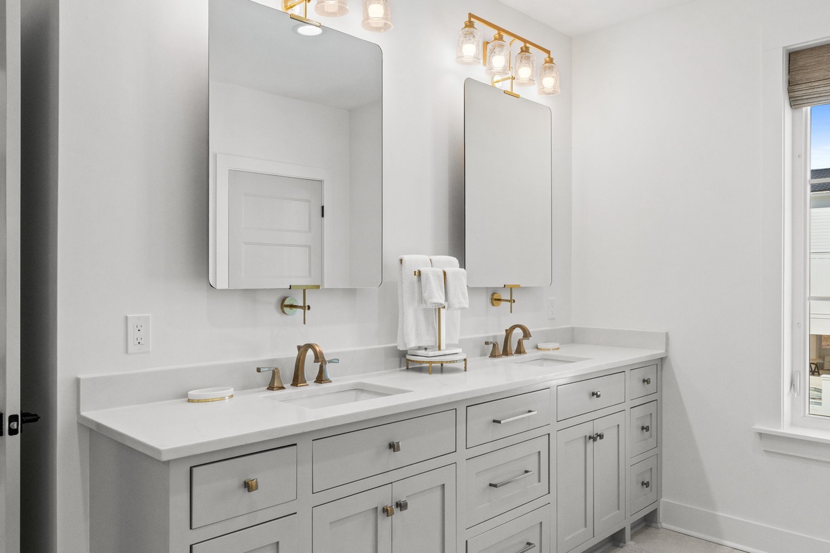 Pamper yourself in this elegant dual-vanity bathroom featuring marble countertops, gold fixtures, and sophisticated lighting for your morning routine.