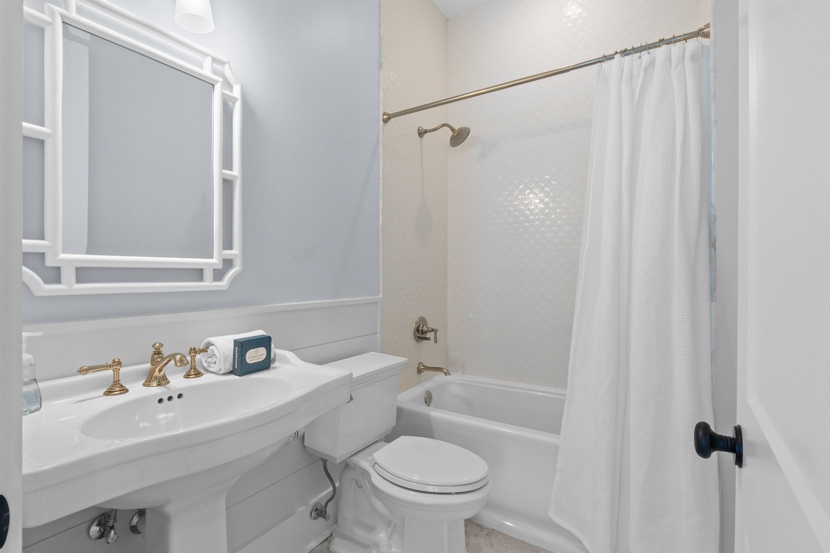 Step into a sparkling, classic bathroom that's all yours—crisp white fixtures, soothing soft blue walls, and a gleaming tub-shower combo await your refreshing escape.