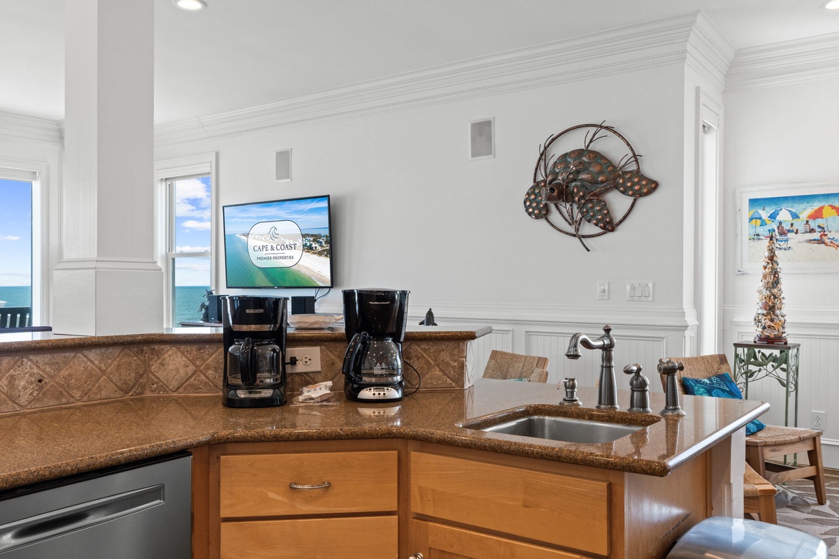 Wake up to ocean views and brew your morning coffee in a bright coastal kitchen with granite counters, dual coffee makers, and beachy decor welcoming you to start your vacation day.
