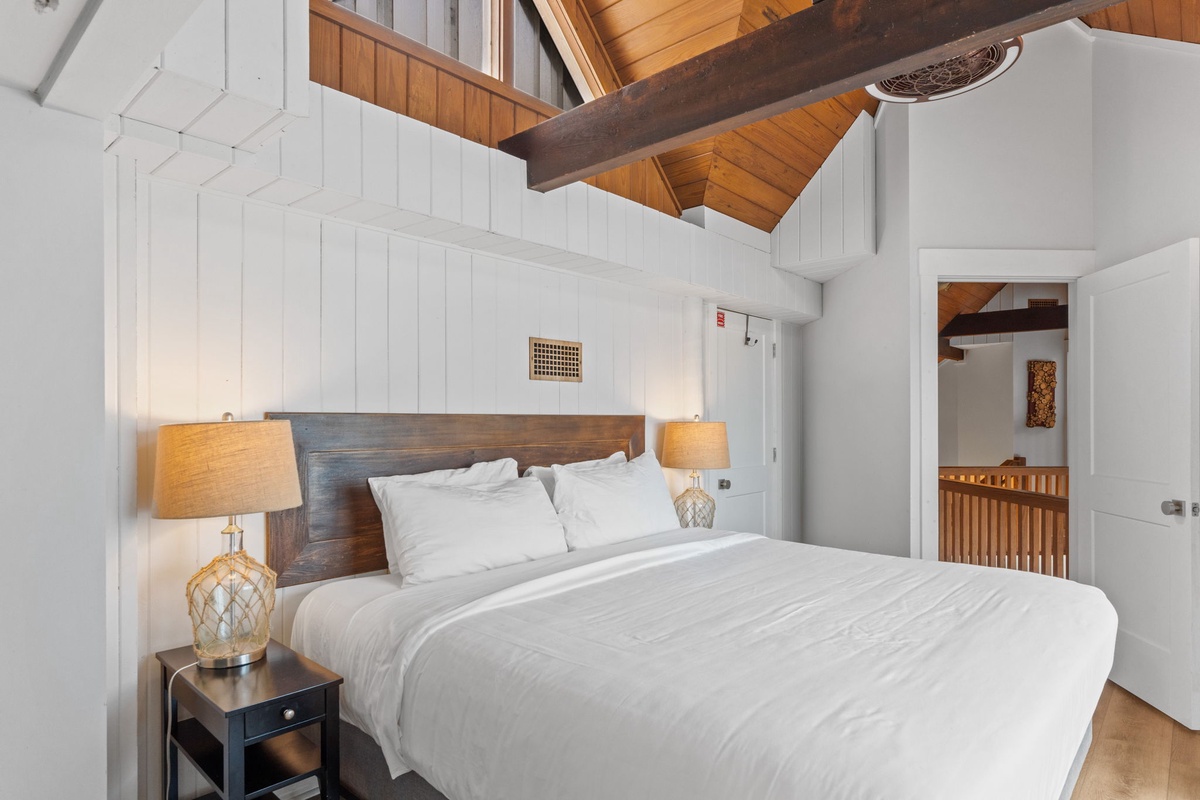 Drift off under vaulted ceilings that blend rustic wood beams with crisp white walls, creating your own serene coastal retreat.