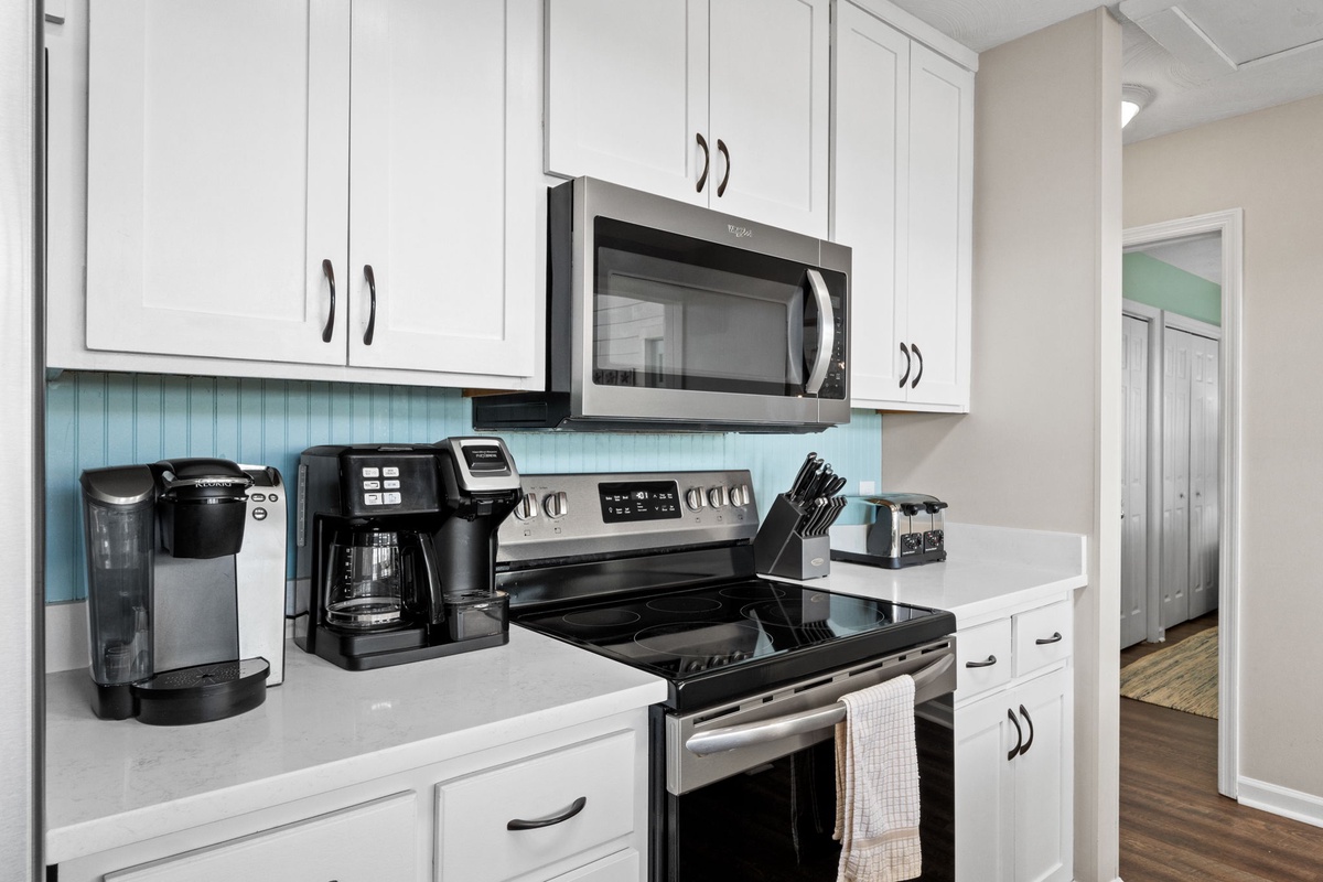 Your modern kitchen features sleek white cabinets, stainless steel appliances, and coffee makers ready for your morning brew.