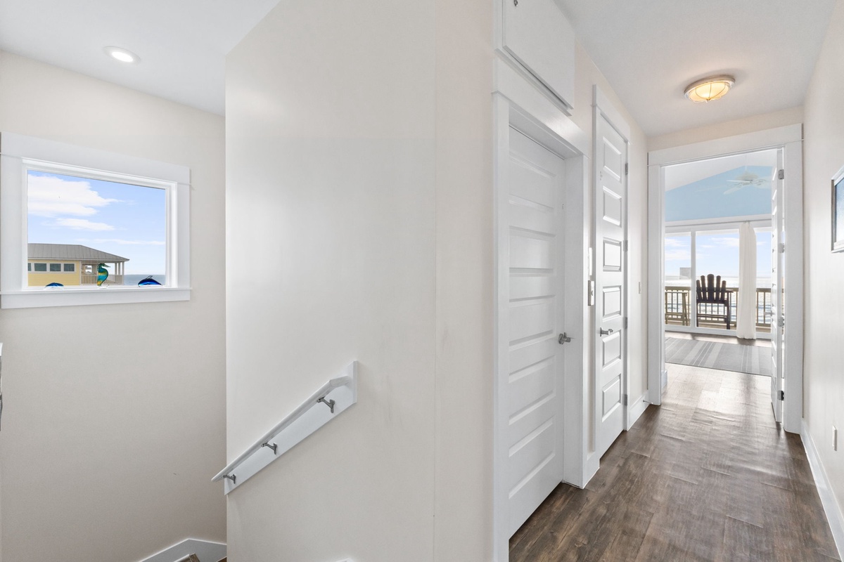 Step into your bright, modern hallway where stylish hardwood floors guide you to breathtaking ocean views and multiple rooms.