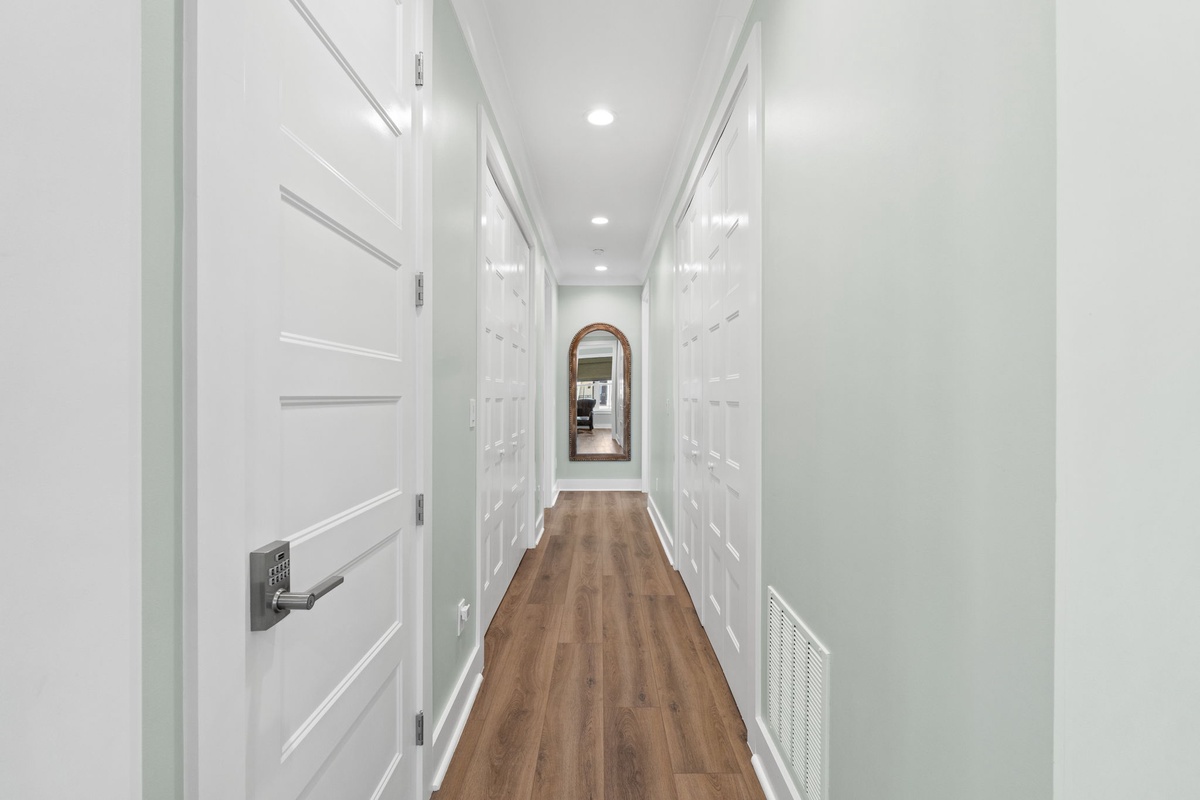 Step into a bright, welcoming hallway with warm wood floors and stylish white doors. Built-in storage keeps your belongings organized, while an arched mirror adds a charming touch.