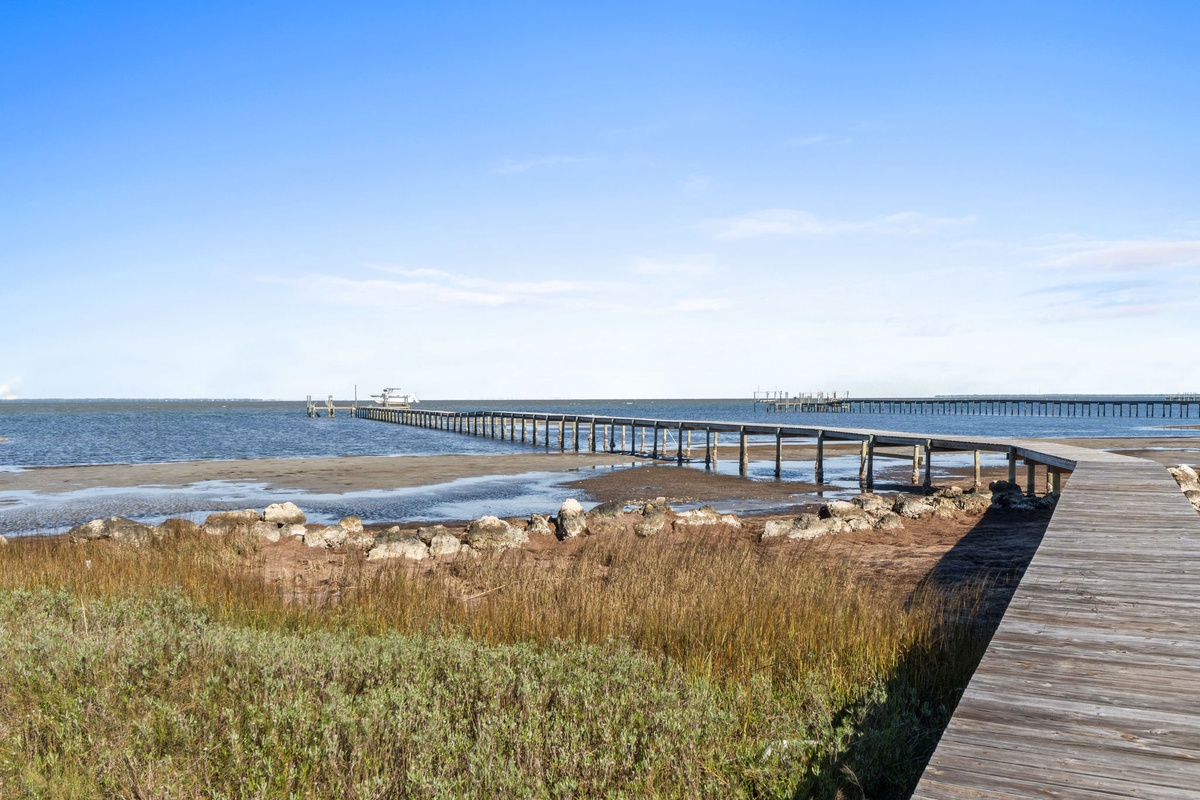 Peaceful wooden boardwalk stretches over tranquil waters under a brilliant blue sky, creating the perfect waterfront escape.