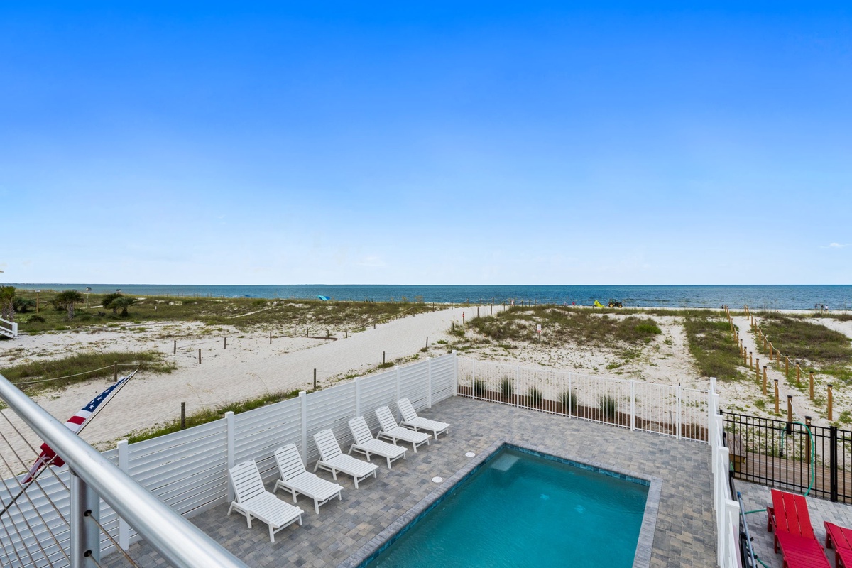 A private beachfront pool area with white loungers sits just steps from pristine white sands and azure waters—your perfect spot to soak up sun and sea breeze.