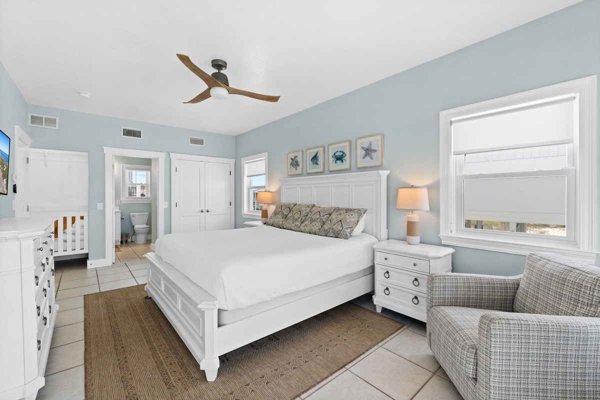 Your bright, coastal bedroom welcomes you with a comfortable king bed, ocean-inspired décor, and calming sea views through large windows. Relax in the cozy armchair or enjoy refreshing breezes from your ceiling fan.