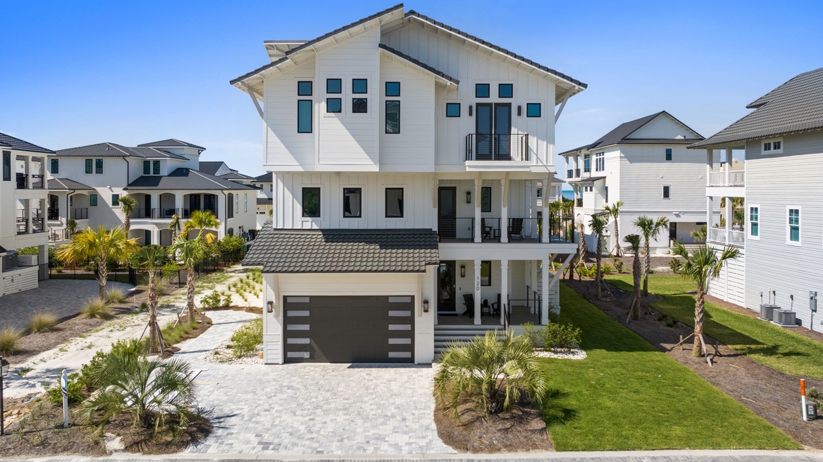 Modern three-story coastal property featuring contemporary architectural design with clean lines, spacious balconies, tropical landscaping, and a prime location in a resort-style neighborhood.