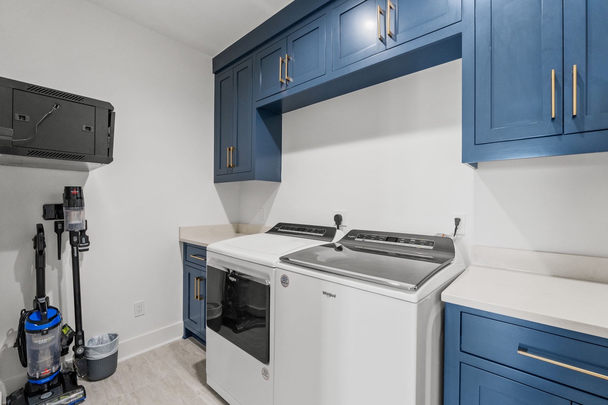Your dedicated laundry space features custom blue cabinetry and modern appliances to keep your vacation wardrobe fresh throughout your stay.
