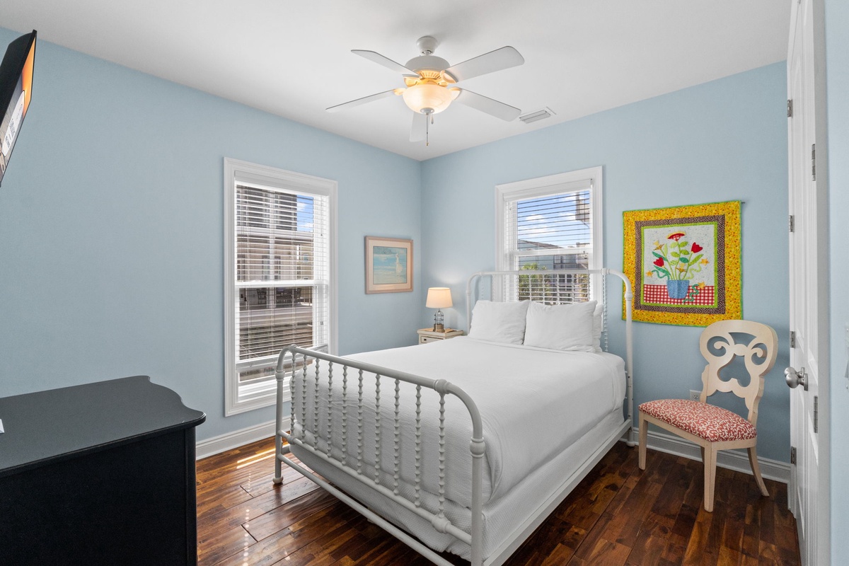 Drift into restful sleep in this cozy bedroom, where soft blue walls and crisp linens create your own peaceful retreat. Natural light streams through double windows, and charming touches make your stay feel like home.