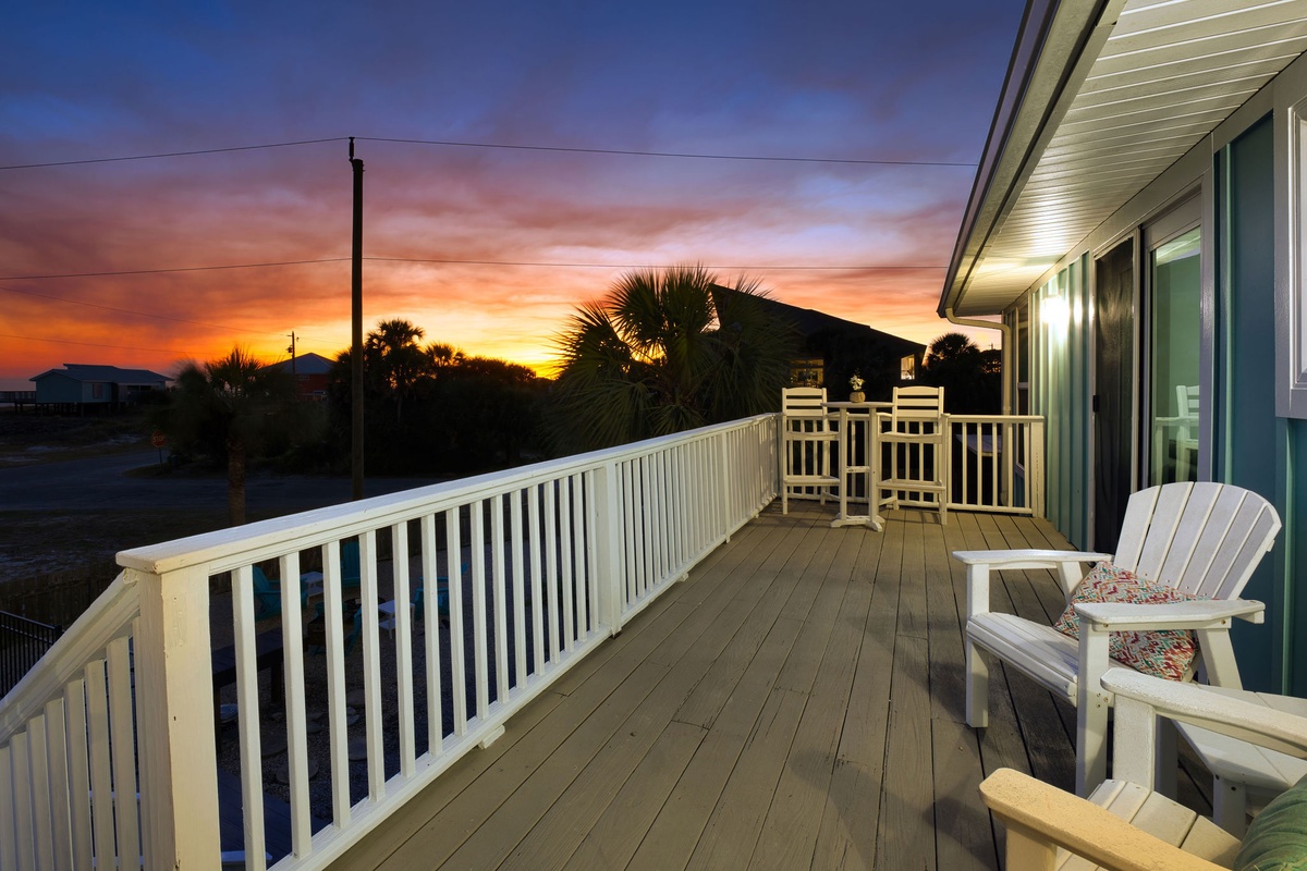 Sunset paints the sky in brilliant colors above this spacious deck with comfortable seating and tropical palm views.