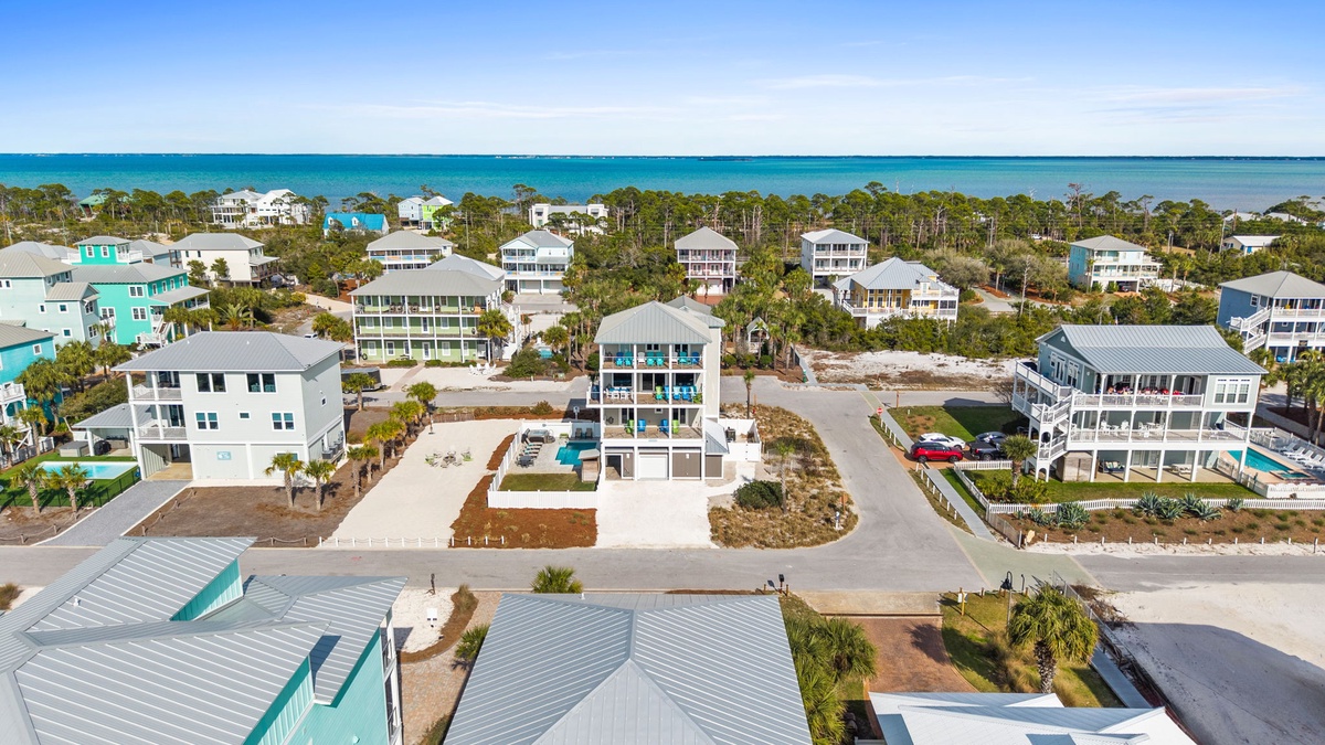 Stunning aerial view of coastal beach homes with turquoise waters and pristine sandy shores stretching into the distance.