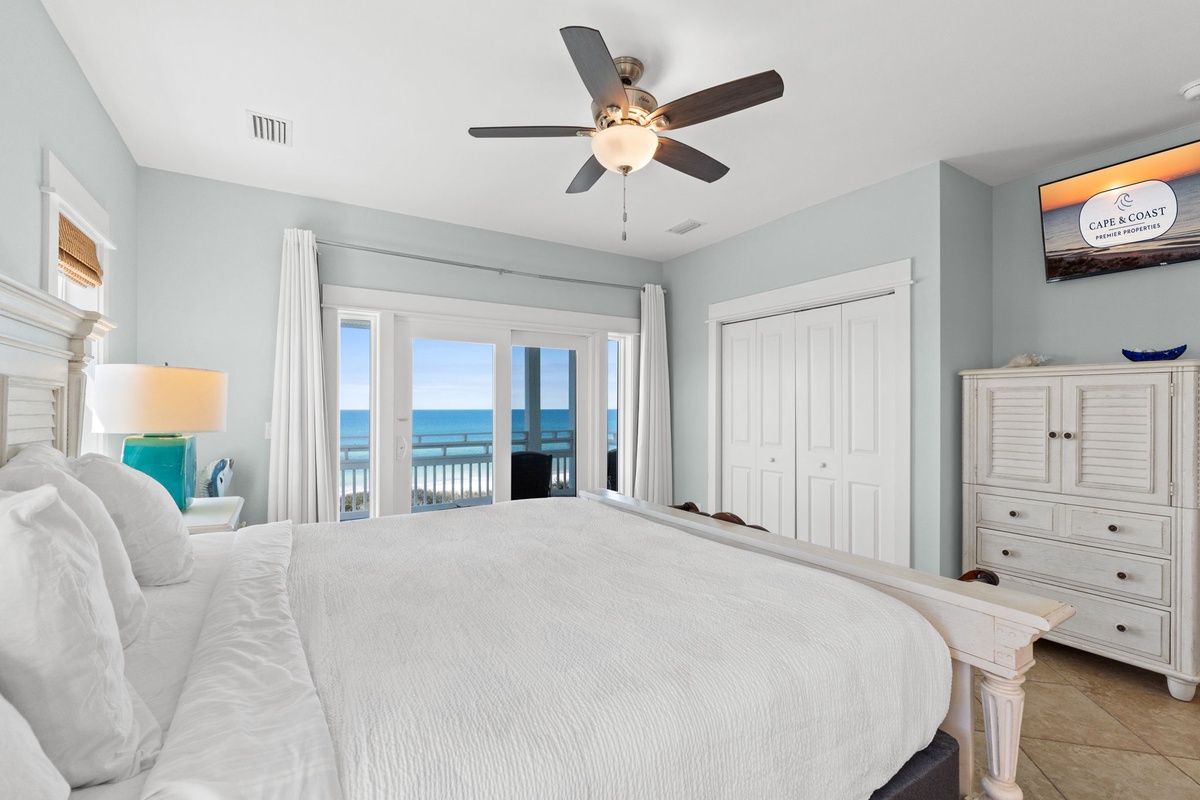 Wake up to stunning ocean views through your private balcony doors in this serene coastal bedroom.