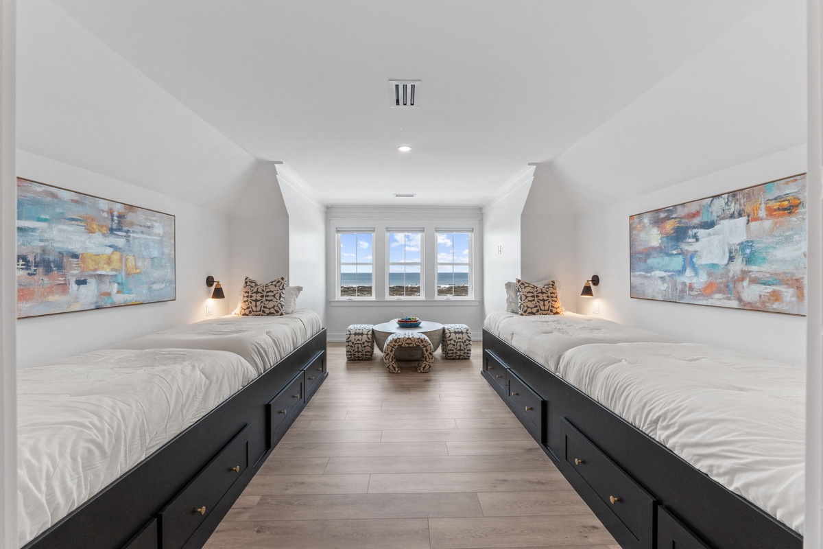 Unwind in your serene twin bedroom featuring crisp linens, built-in storage, and coastal artwork creating the perfect peaceful retreat.
