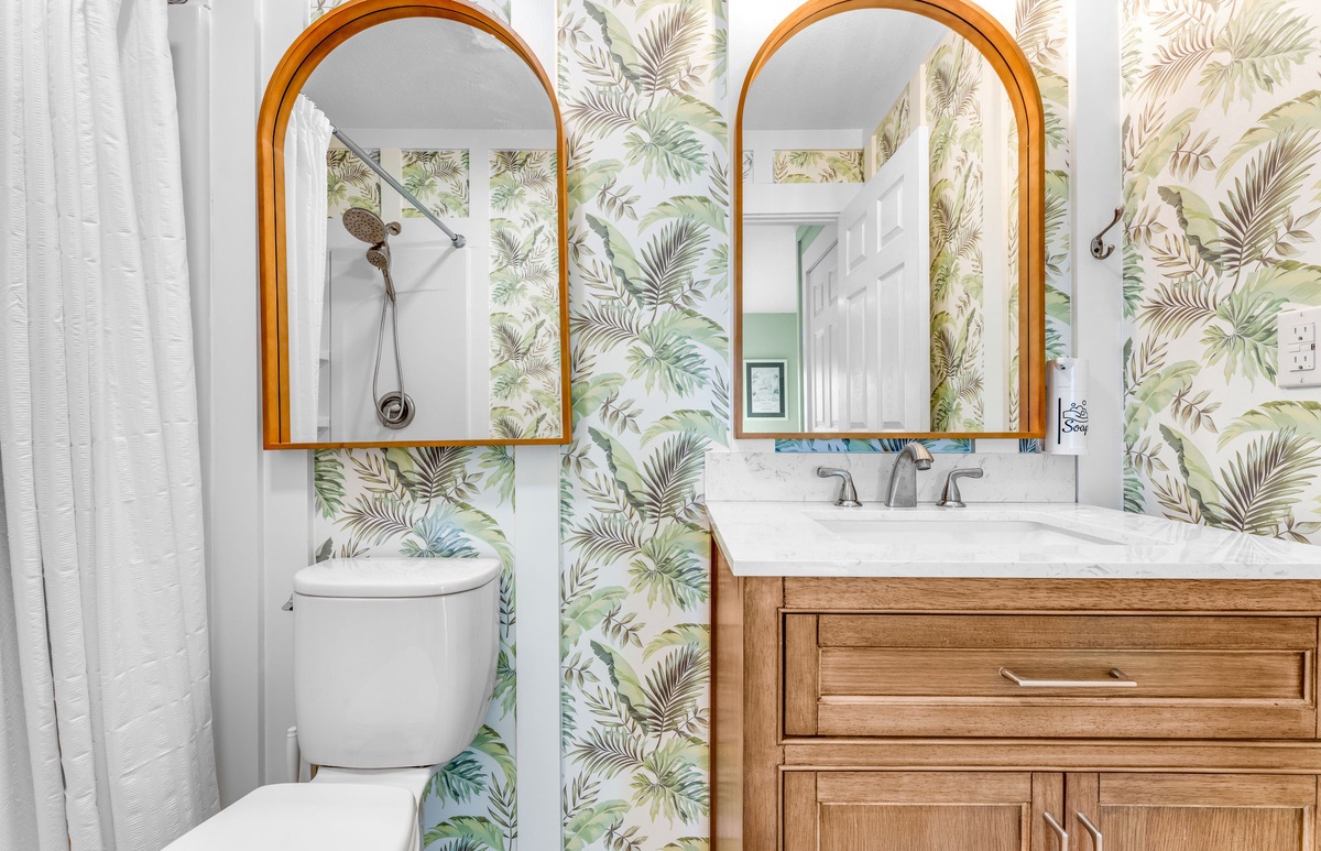 Step into your tropical oasis bathroom where lush palm wallpaper and warm wood vanity create a serene spa-like retreat.