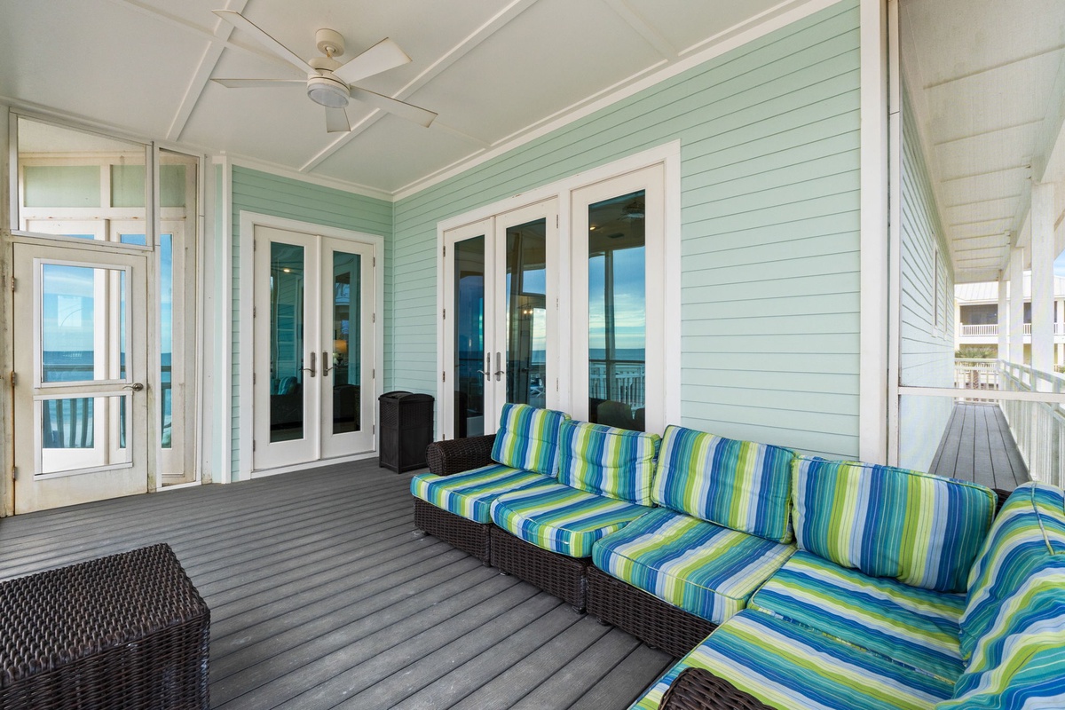 Your covered porch beckons with vibrant striped seating and ocean breezes, perfect for morning coffee or sunset relaxation.