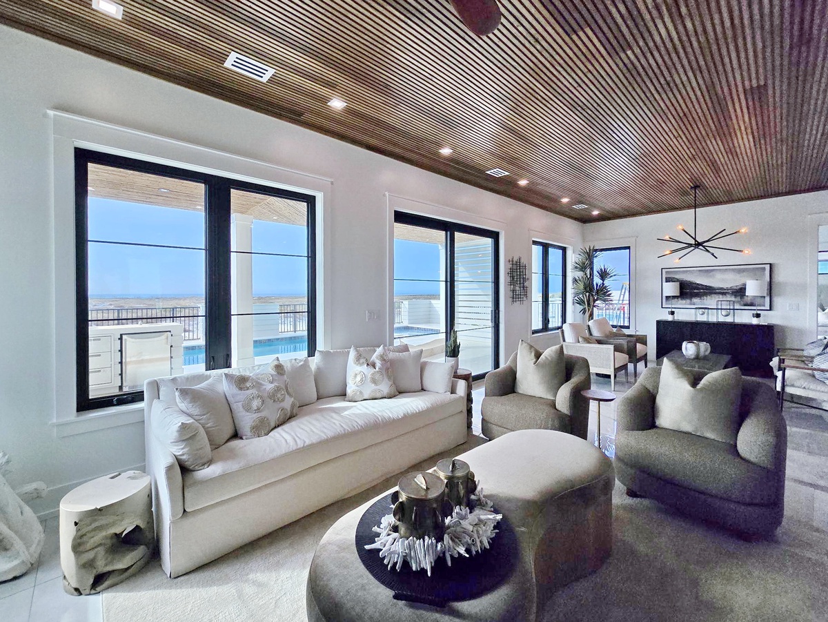 Your sophisticated living space features plush seating and stunning ocean views through floor-to-ceiling windows—perfect for watching sunsets over cocktails.
