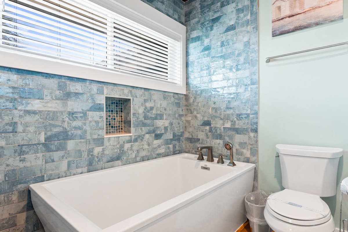 Soak away the day in your spa-like bathroom, where ocean-inspired tiles and a crisp white tub create a serene coastal retreat.