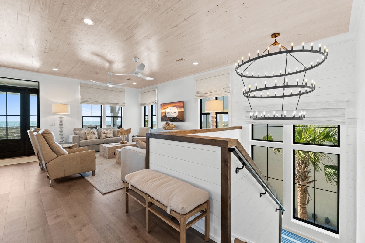 Unwind in your sophisticated living space featuring warm wood ceilings, designer lighting, and stunning windows framing tropical views.