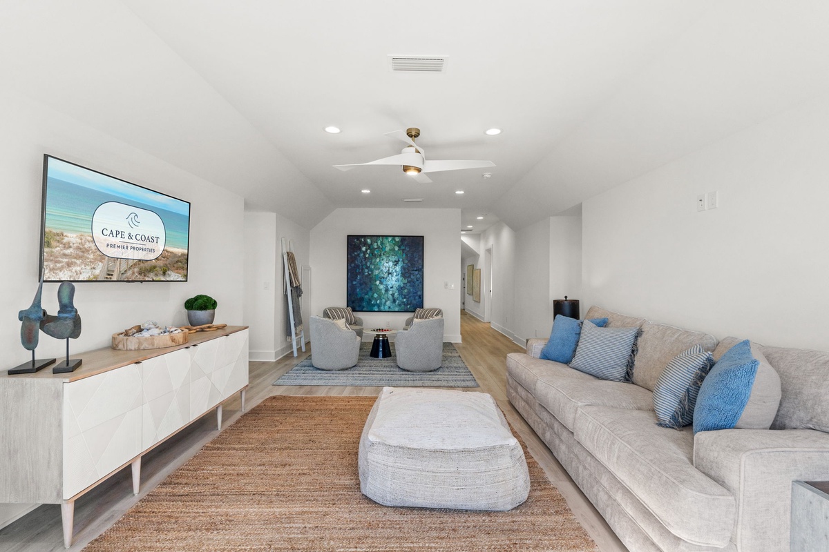 Unwind in your spacious living room with plush seating, coastal artwork, and entertainment center for perfect relaxation.