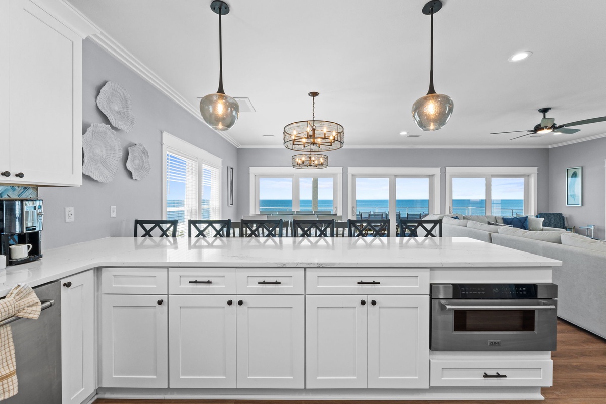Gather around this spacious island and watch the sun dance on ocean waves through oversized windows. The open-concept design invites you to cook, dine, and relax without missing a moment of that stunning sea view.